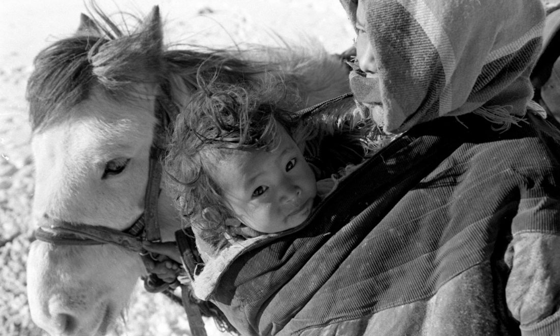 1990年3月，西藏當(dāng)雄縣納木湖鄉(xiāng)三村女牧民斯卓不畏嚴(yán)寒，懷抱幼子，準(zhǔn)備到遠(yuǎn)處放牧。新華社記者覺果攝