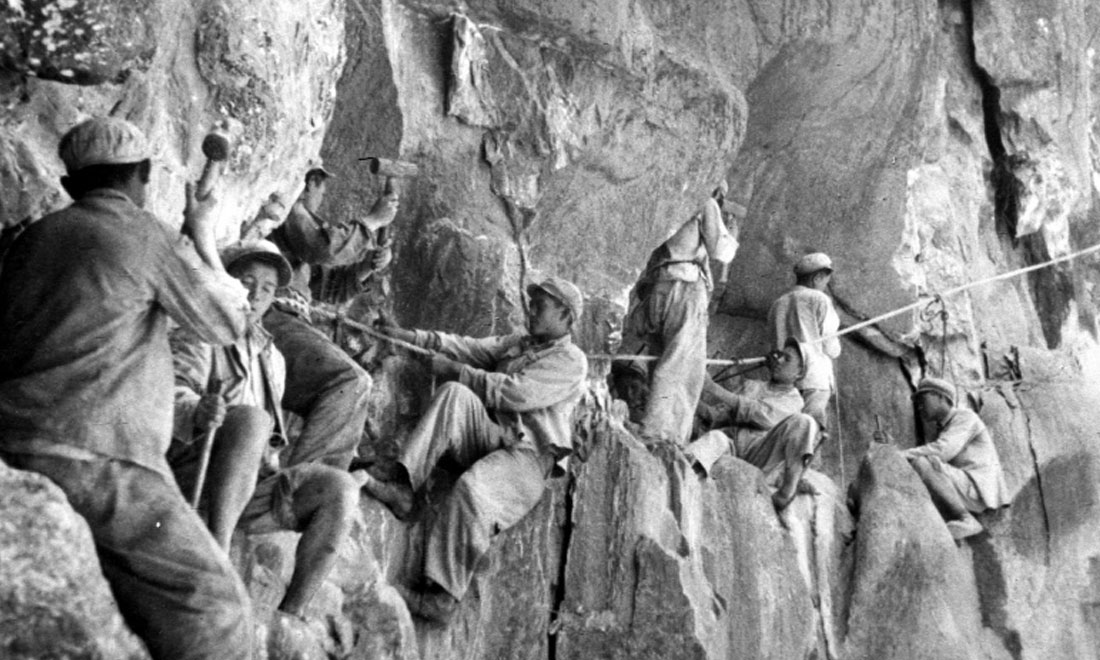 1954年，修筑康藏公路的解放軍戰(zhàn)士們?cè)谂瓋砂兜膽已露副谏媳偕街?。新華社稿 李萬春、張加里攝